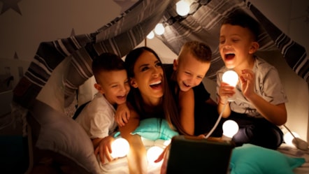 Family in duvet fort with lights