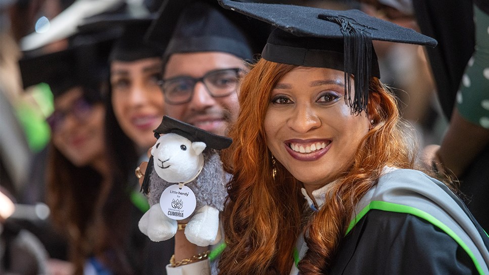 Graduation ceremonies inside Carlisle Cathedral.
Graduate in academic robes holding a 'graduation' Herdy stuffed toy