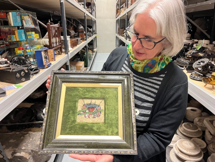 Biscuit messages: Curator Kitty Ross with the decorated biscuit from 1914, beautifully painted with an image of a battleship and carrying an inscription that reads ‘Wishing you a Merry Christmas and a bright new year’.
The fragile vintage snacks, more than a century old, were originally issued to servicemen as a durable emergency ration but were reputedly so unpalatable, they were instead repurposed as a humorous way of staying in touch with loved ones over Christmas.
