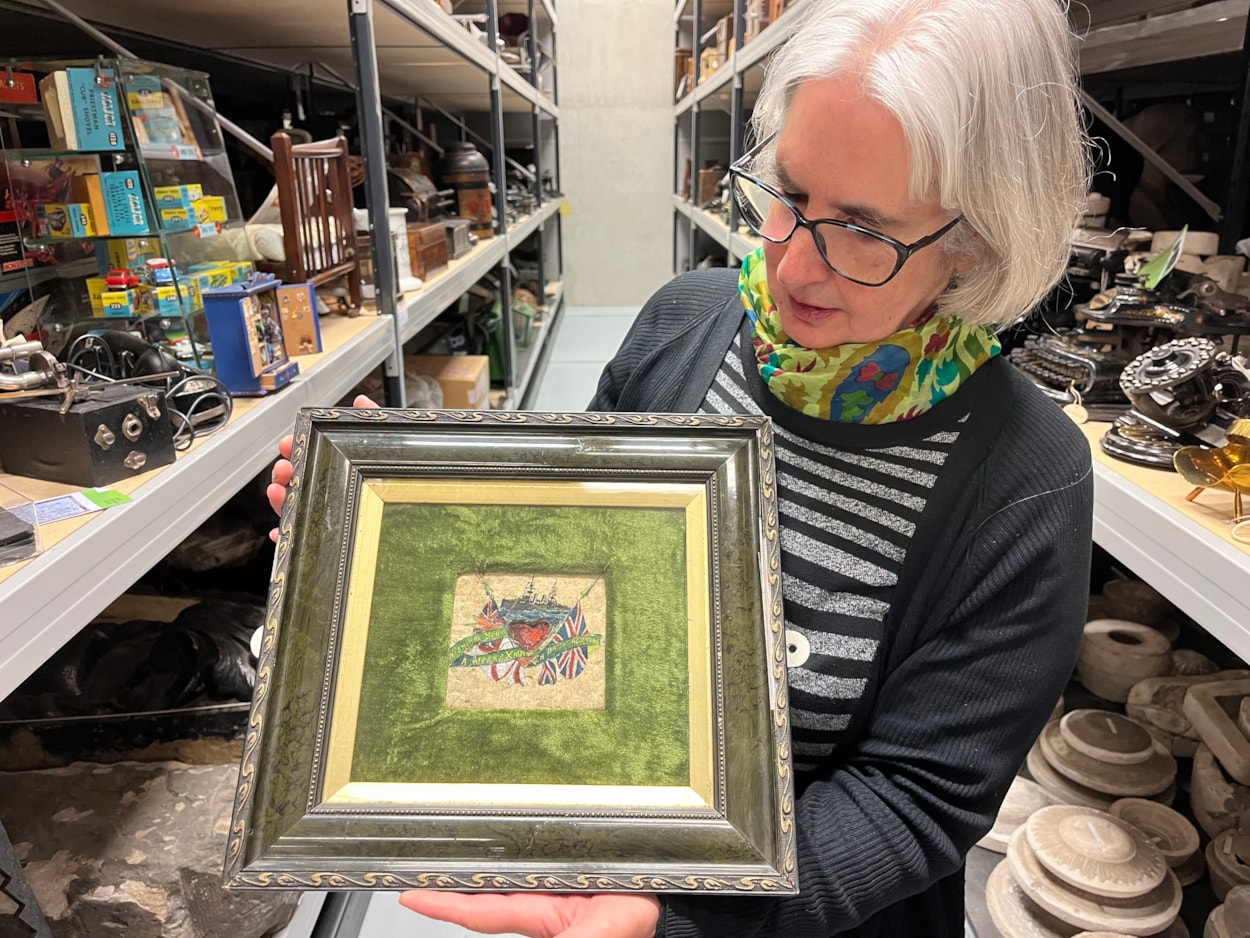 Biscuit messages: Curator Kitty Ross with the decorated biscuit from 1914, beautifully painted with an image of a battleship and carrying an inscription that reads ‘Wishing you a Merry Christmas and a bright new year’.
The fragile vintage snacks, more than a century old, were originally issued to servicemen as a durable emergency ration but were reputedly so unpalatable, they were instead repurposed as a humorous way of staying in touch with loved ones over Christmas.