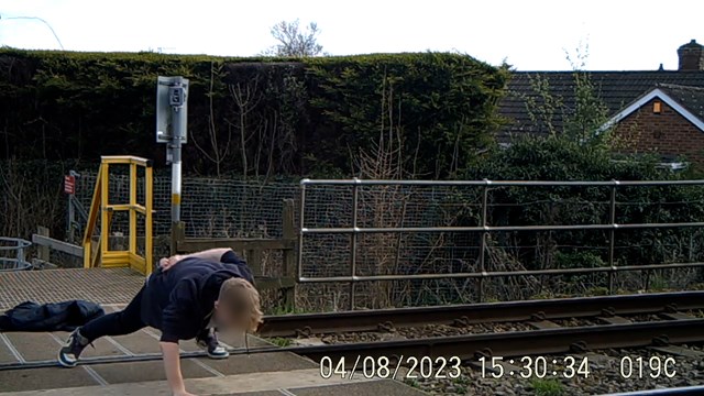 Youth doing on armed press ups on level crossing while listening to loud music: Youth doing on armed press ups on level crossing while listening to loud music