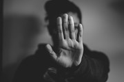 Domestic Abuse Strategy image - Dec 19: A black and white photograph of a woman holding her hand up in front of her, palm facing the camera. The palm of her hand is in focus and obscuring her face. The woman is out of focus.