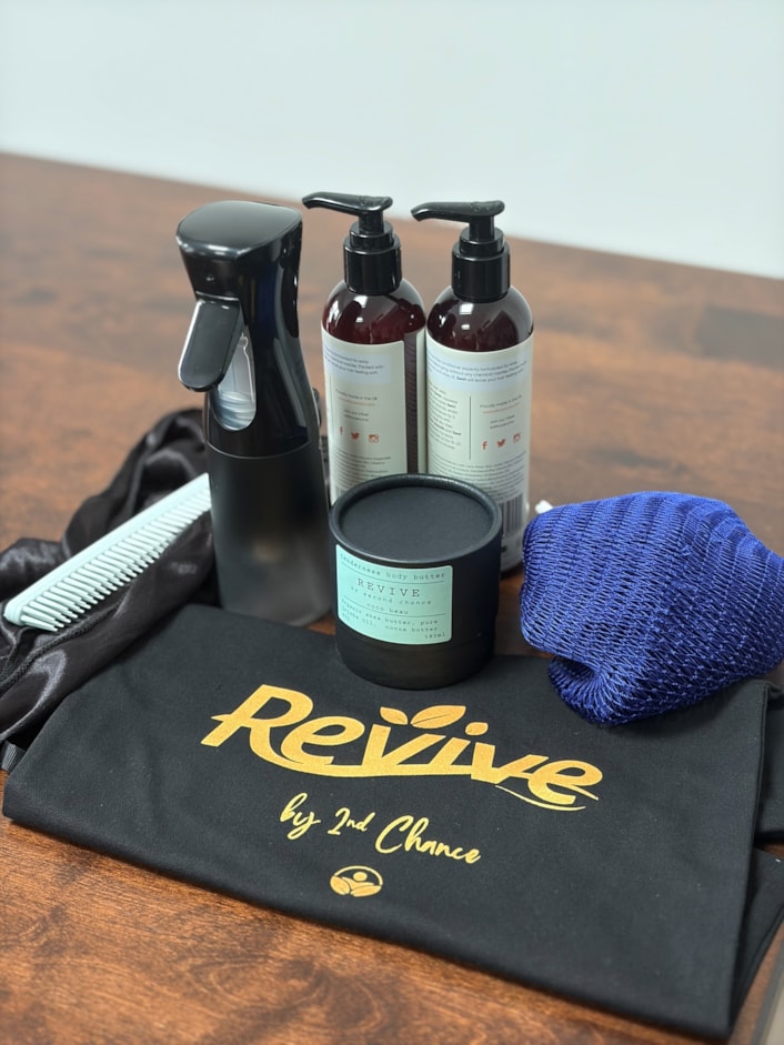 RevivebySecondChance 4: Image shows an empty black bag, with products on top, including a pot of skin cream, a spray bottle and men's durag and comb.