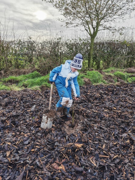 One of the schoolchildren planting a sapling