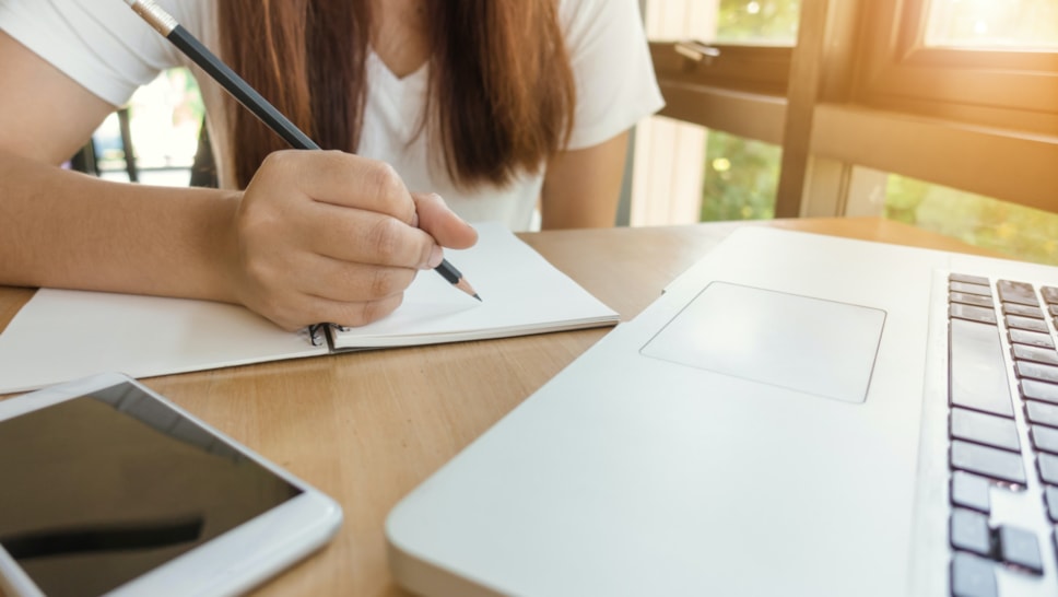 Woman writing by laptop