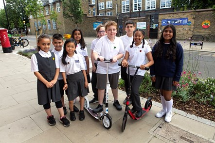 Schoolchildren pose outside Robert Blair Primary School. Two of them are holding scooters