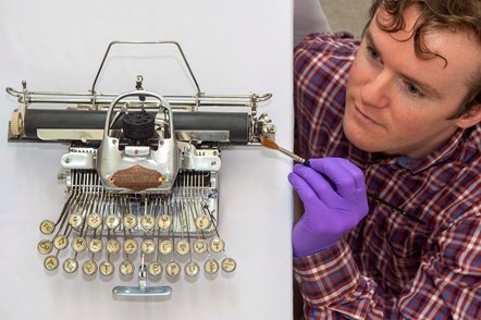 PhD student James Inglis brushing a Blickensderfer featherweight typewriter with a paintbrush. Photo © Neil Hanna