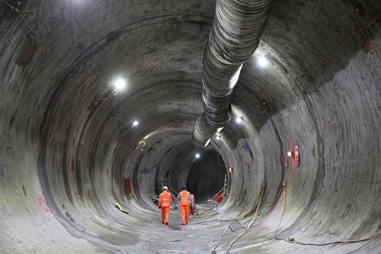 View inside a sprayed concrete lined tunnel beneath HS2's Euston Station: Engineers walking through the traction substation tunnel beneath HS2's Euston Station.