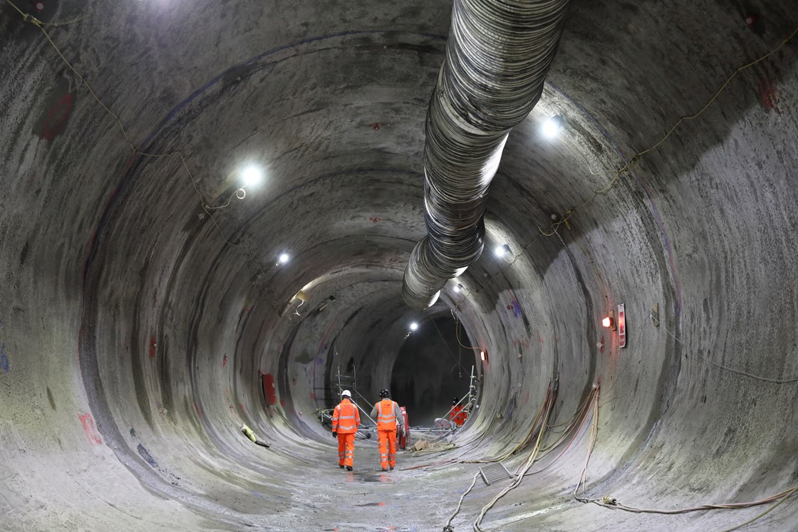 View inside a sprayed concrete lined tunnel beneath HS2's Euston Station: Engineers walking through the traction substation tunnel beneath HS2's Euston Station.