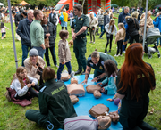 Party for Hilsea - NHS ambulance service: Photo taken at Party for Hilsea in 2022. Image shows four NHS ambulance service workers demonstrating to families CPR techniques on dummies.