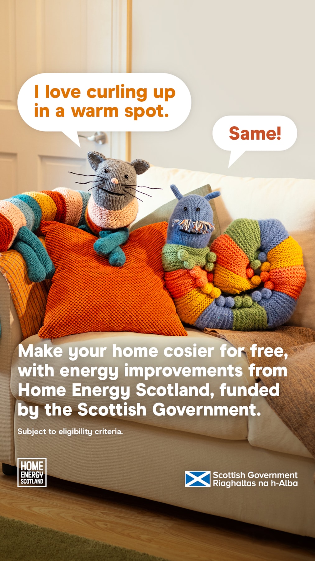 Knitted cat and snake with speech bubbles saying 'I love curling up in a warm spot' and 'Same!' on a couch. Text promotes free energy improvements from Home Energy Scotland, funded by the Scottish Government. Logos and eligibility note included.