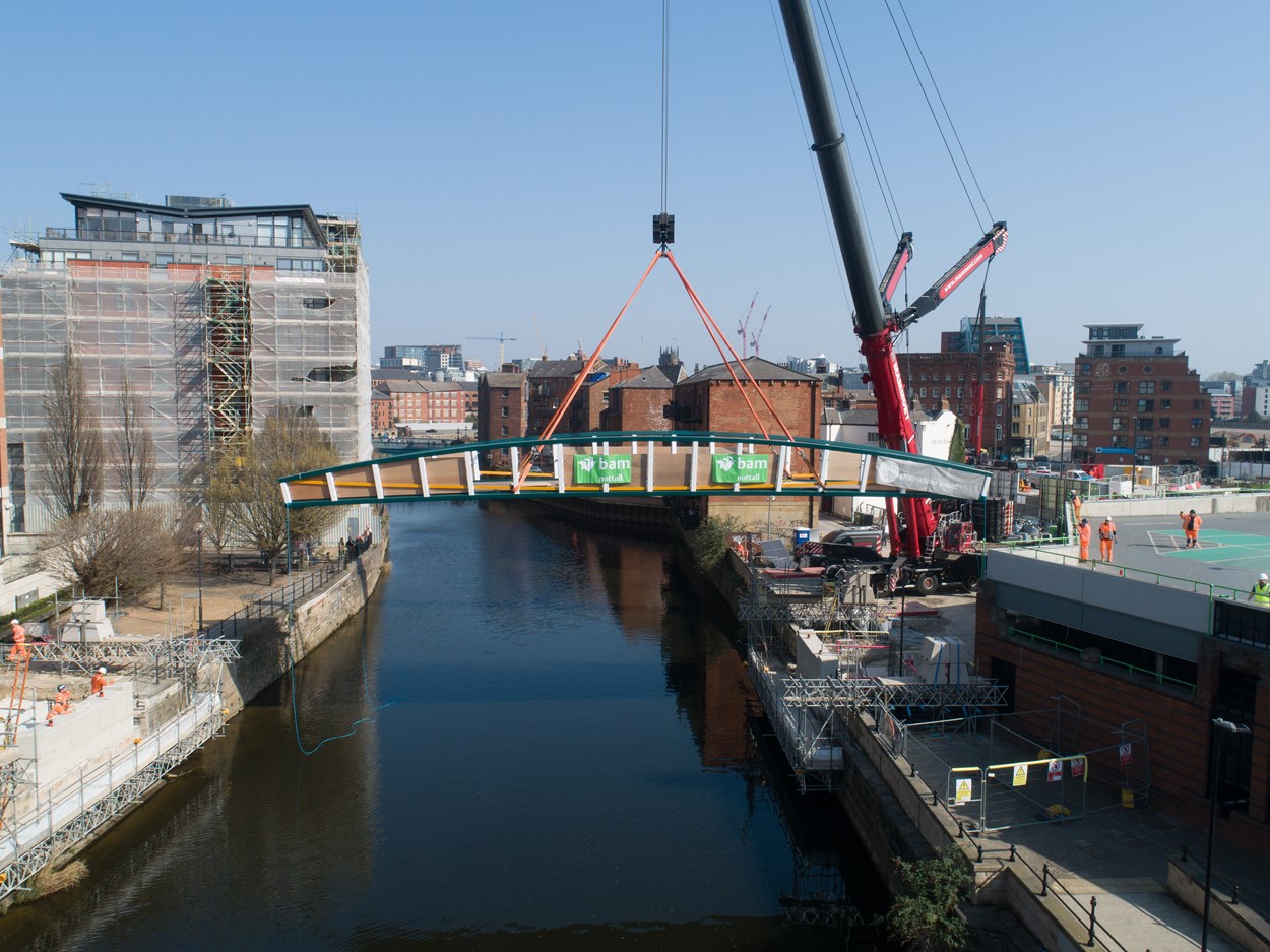 David Oluwale bridge installation: The David Oluwale bridge is lifted into place over the River Aire in Leeds. Engineers working on the David Oluwale bridge completed one of the project’s major milestones over the weekend, with cranes carefully placing the 40 tonne structure over the river where it will connect Sovereign Street to Water Lane. Credit BAM Nuttall.