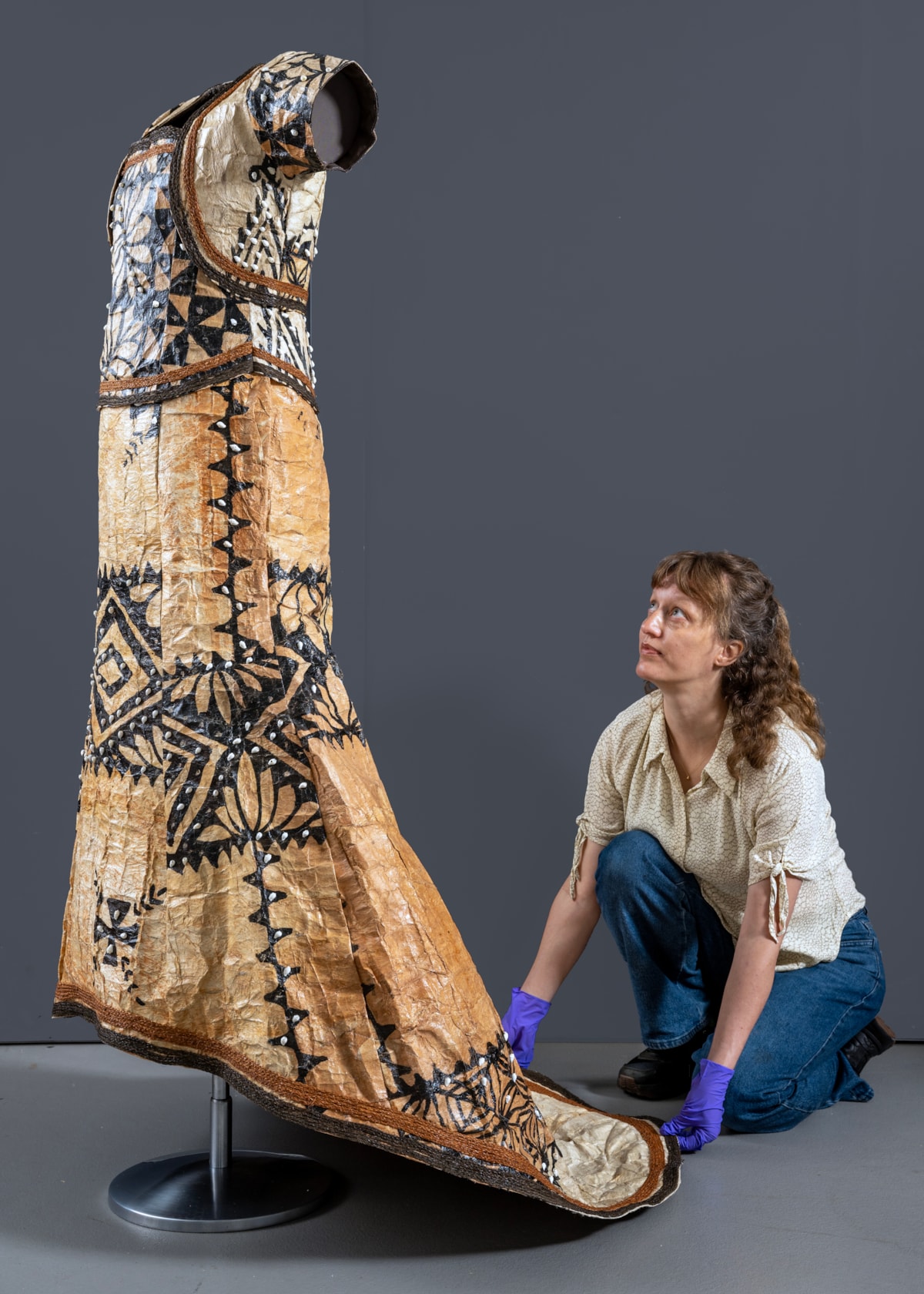 Conservator Emma Pattinson prepares the barkcloth wedding dress for display. Photo © Neil Hanna