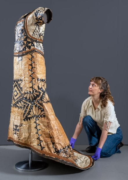 Conservator Emma Pattinson prepares the barkcloth wedding dress for display. Photo © Neil Hanna