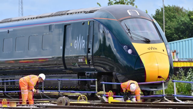 Train services to be reinstated between Exeter and Copplestone, but line to Barnstaple remains suspended due to ongoing adverse weather conditions: Engineers on track with GWR train passing by