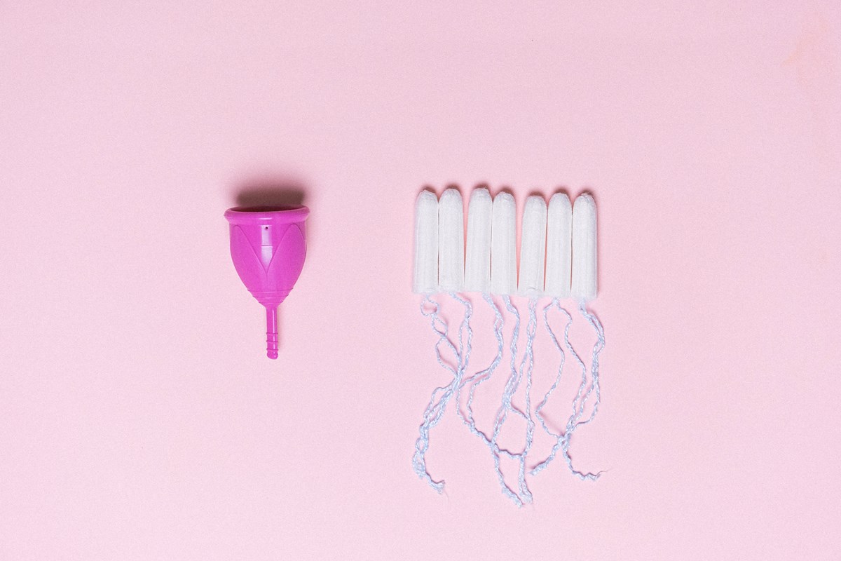Period Products photo by Anna Shvets at Pexels: Menstrual cup and tampons are lined up on a pink background.