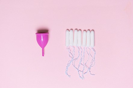 Menstrual cup and tampons are lined up on a pink background.