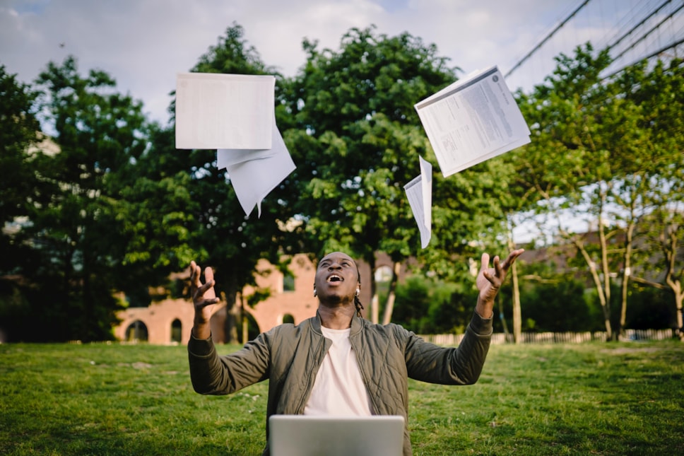 young black  male student throwing papers in the air