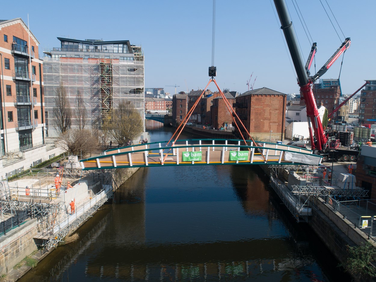 David Oluwale bridge installation: The David Oluwale bridge is lifted into place over the River Aire in Leeds. Engineers working on the David Oluwale bridge completed one of the project’s major milestones over the weekend, with cranes carefully placing the 40 tonne structure over the river where it will connect Sovereign Street to Water Lane. Credit BAM Nuttall.