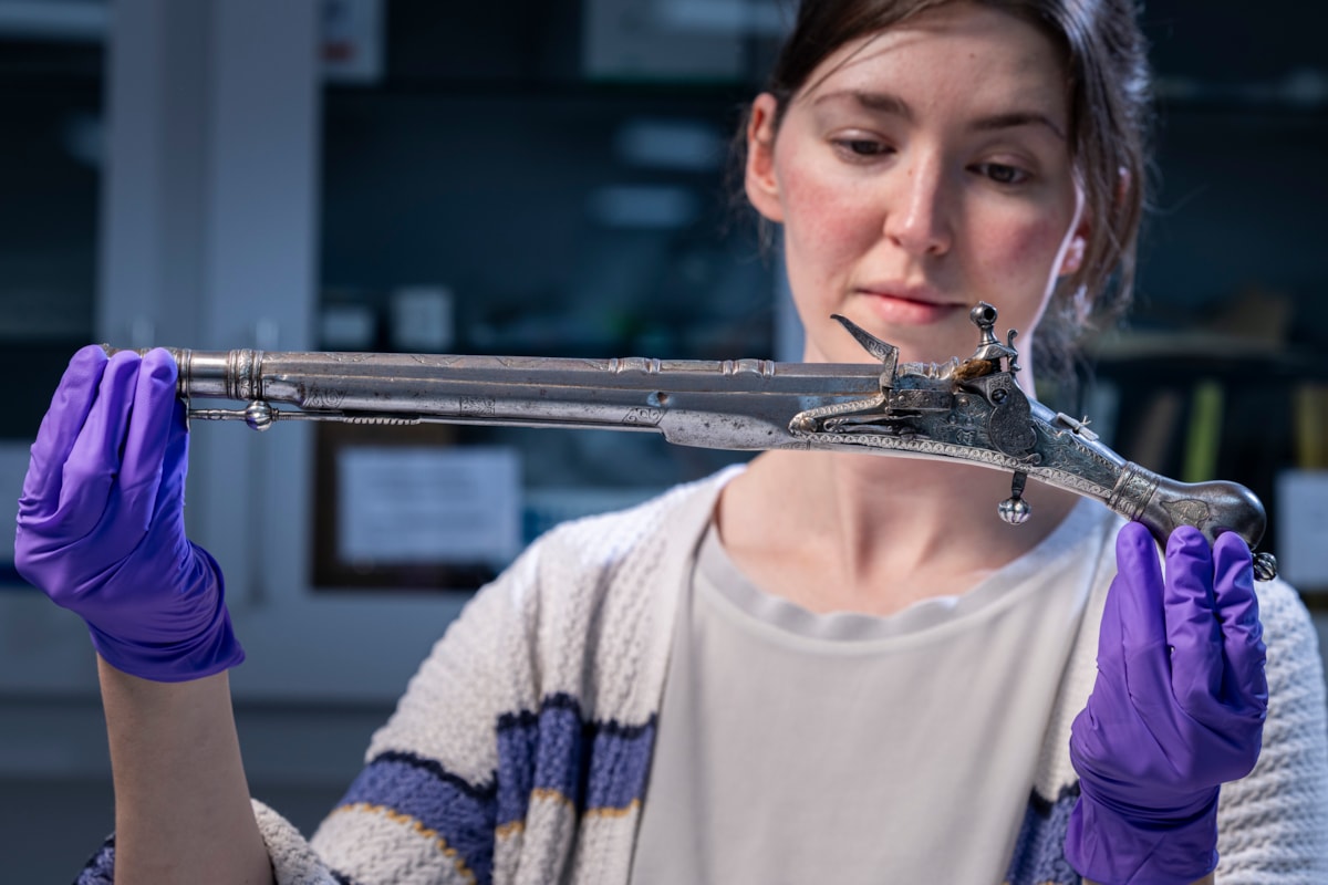Curator Ella Paul examines the pistol at National Museums Scotland. Image © Duncan McGlynn (2)