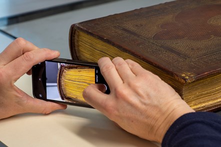 A Library conservator inspects the Library's copy of the Gutenberg Bible before it is installed at the Treasures of the National Library exhibition. Credit: Neil Hanna