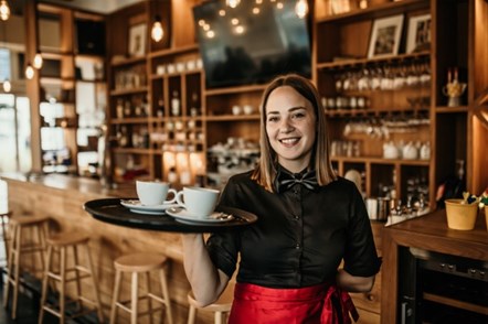 Waitress with long, straight brown hair smiling with tray of coffee