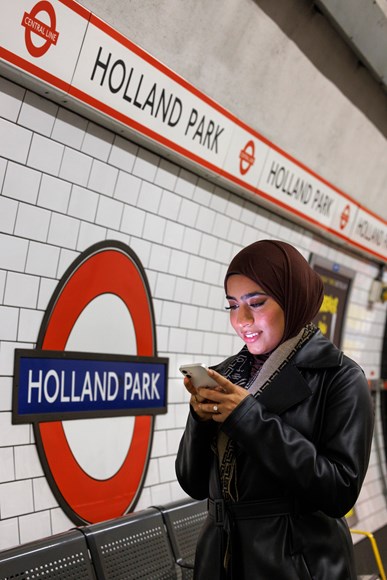 TfL Passenger using mobile on Holland Park platform