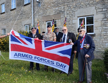 Serving troops and veterans holding the Armed Forces Day flag