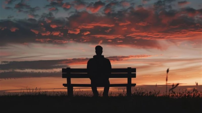 Drug and alcohol strategy 1: Image shows the silhouette of a man sitting on a bench looking out to a sunset