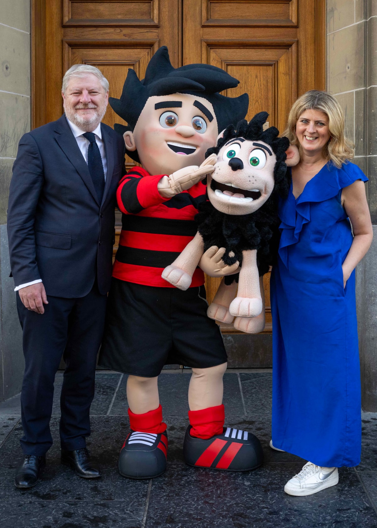 National Librarian and Chief Executive of the National Library of Scotland, Amina Shah and Cabinet Secretary for Constitution, External Affairs and Culture with Dennis the Menace outside the Library's George IV Bridge building. Credit: Neil Hanna