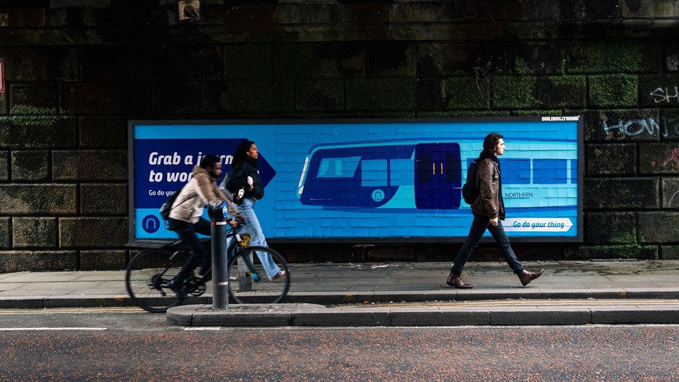 Image shows 'Try The Train' billboard on Manchester Oxford Road