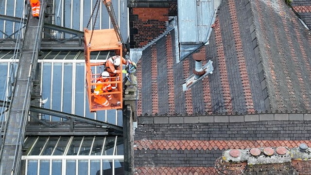Close up of workers removing a finial from Stoke station's roof