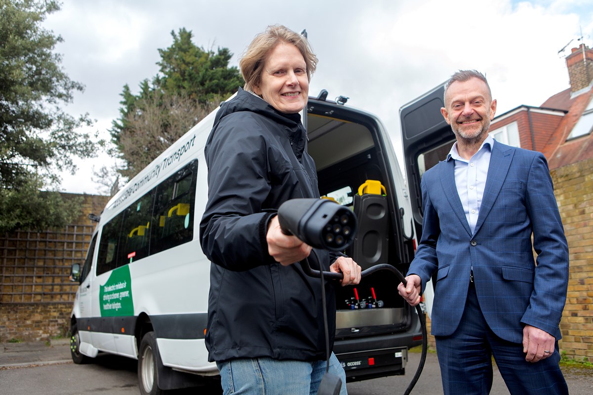 Cllr Champion and Keith Townsend pose with an electric charger, standing in front of Islington's new 17-seater electric minibus