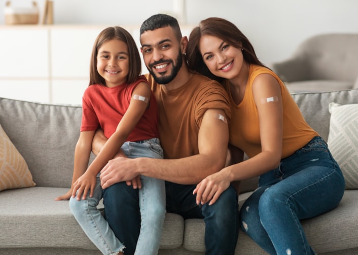 Happy vaccinated family showing plasters at home