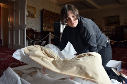 Lynda Jackson, Museum Manager, examines a walking dress for display from around 1825