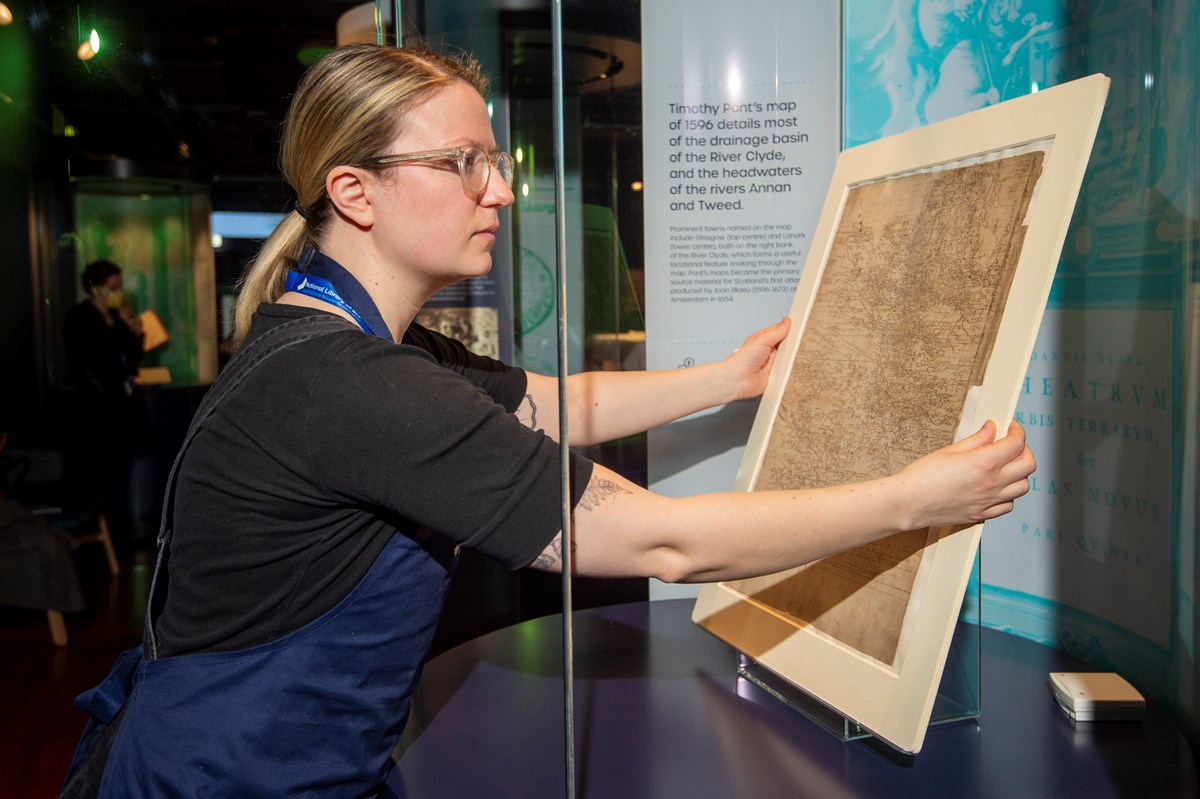 Library Conservator Lizzie Fuller installs a Timothy Pont map (1596)  - detailing most of the drainage basin of the River Clyde. Credit: Neil Hanna