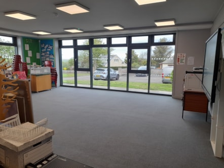 Refurbished classroom with large windows, grey flooring, ceiling lights and an interactive whiteboard.