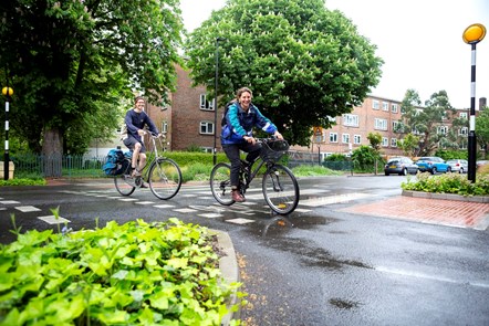 Two cyclists on a zebra crossing in Benwell Road, in the Highbury people-friendly streets neighbourhood