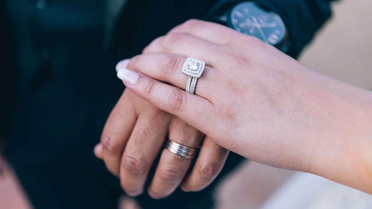 couple holding hands with wedding rings cropped