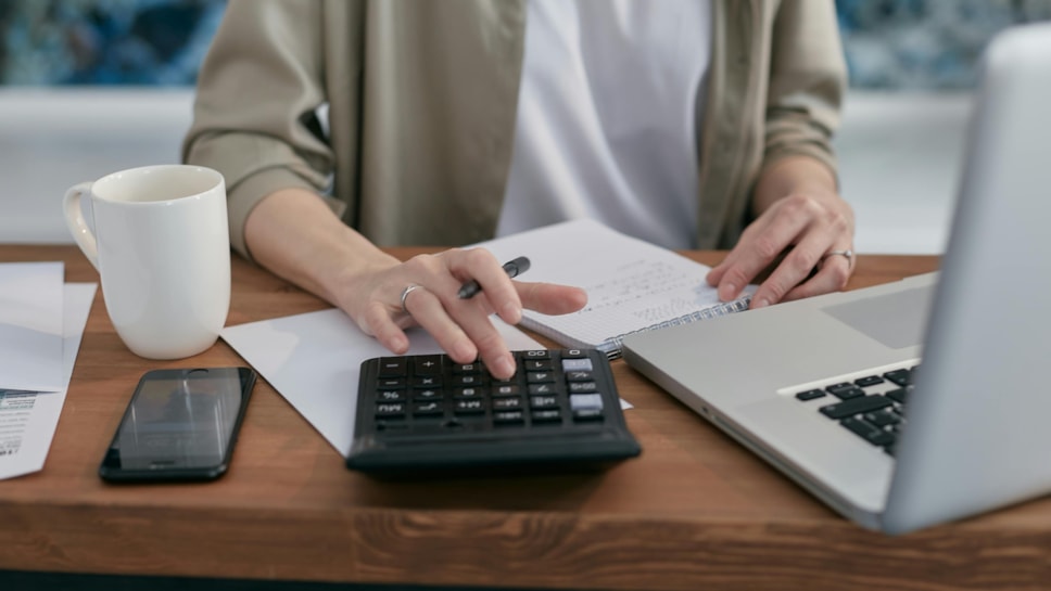 Person with laptop, paperwork and calculator