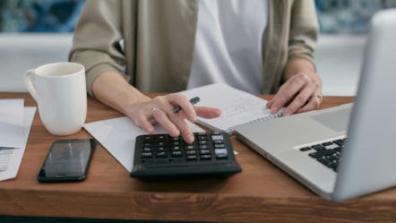Person with laptop, paperwork and calculator