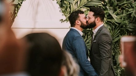 men-wearing-suit-kissing-in-front-of-people-3491999