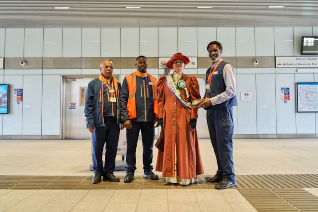 TfL Image - An actress from Zoom through History dressed as Suffragette leader, Emmeline Pankhurst with staff at Barking Riverside station