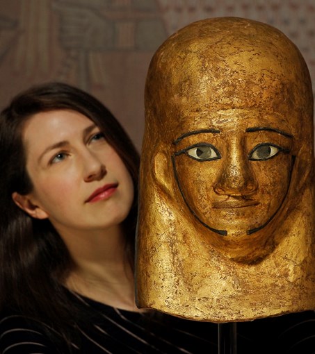 Exhibition curator Dr Margaret Maitland with the gilded mummy mask of Montsuef. Copyright Neil Hanna