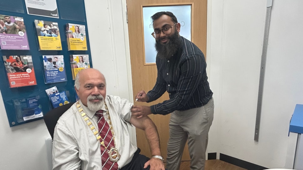 Deputy Mayor Councillor Mushtaq Hussain recives his vaccine at Well Pharmacy at The Northway from pharmacist Thanvir Choudhury