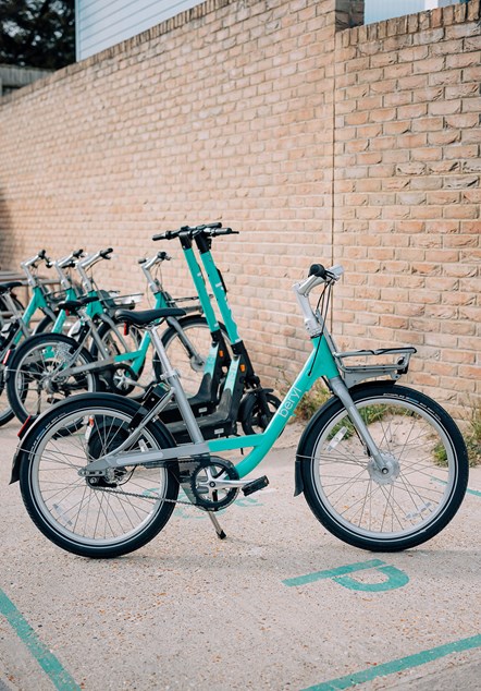 A large wall in front of a Beryl bay containing parked bikes and e-scooters.