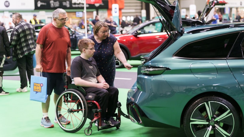 The Big Event 2024: A family of three look in the boot of a car. The sits in a wheelchair and his parents stand either side of him.