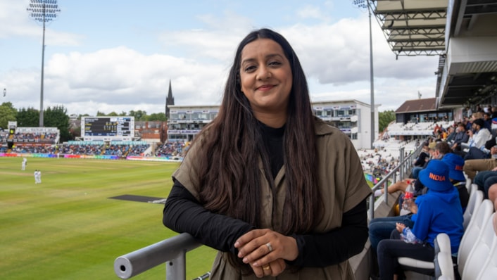 ICC Women's T20 World Cup: Councillor Salma Arif is pictured smiling at the camera, standing on the terraces of Headingley ground, with players in the background.