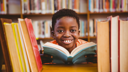 Image of child reading a book in a library