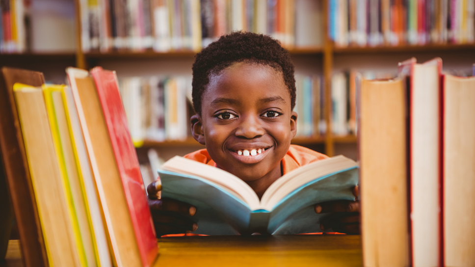 Image of child reading a book in a library